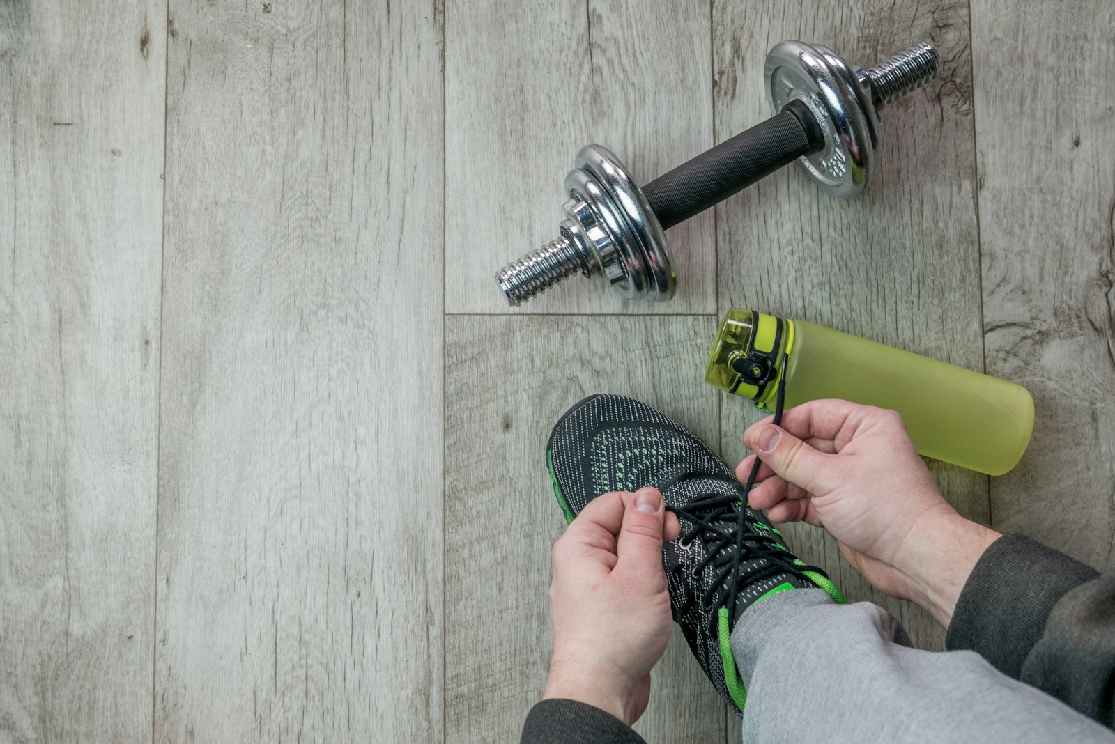 a male American gym rat taking a break and pickup his gym water bottle while tying shoes